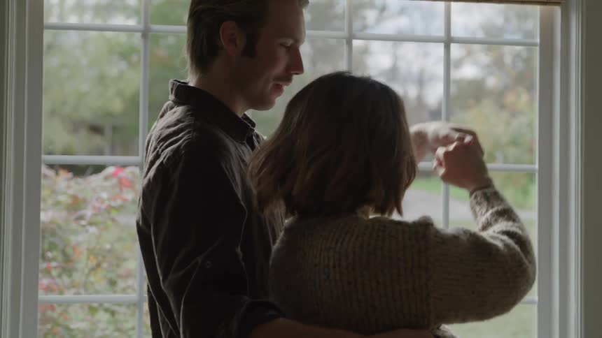 Couple dances smiling in front of a window lit by daylight