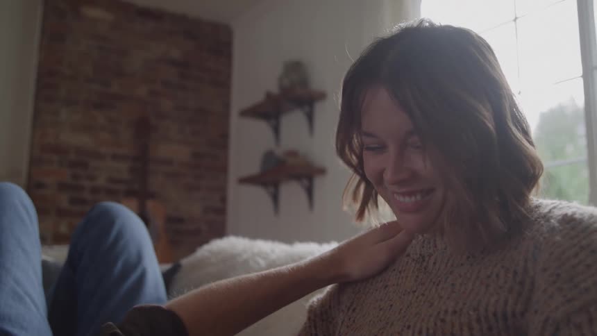 A young couple conversing on a couch in a living room during daytime