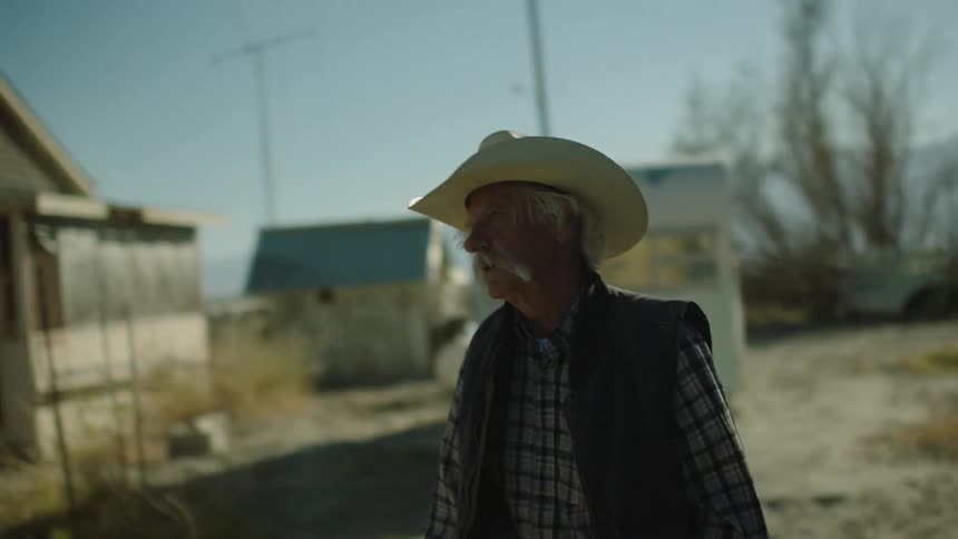 A man with a cowboy hat is walking and searching for something or someone