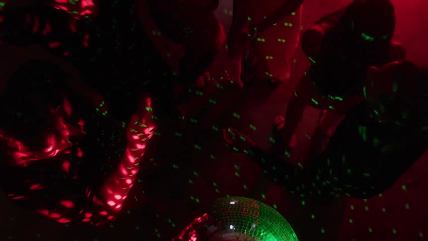 A group of young adults dancing under disco lights in a club at night