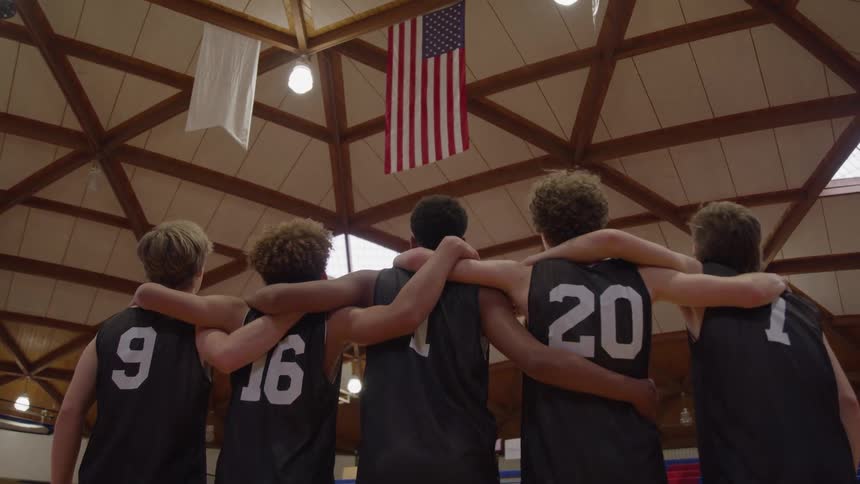 A team of athletes stands in front of an american flag
