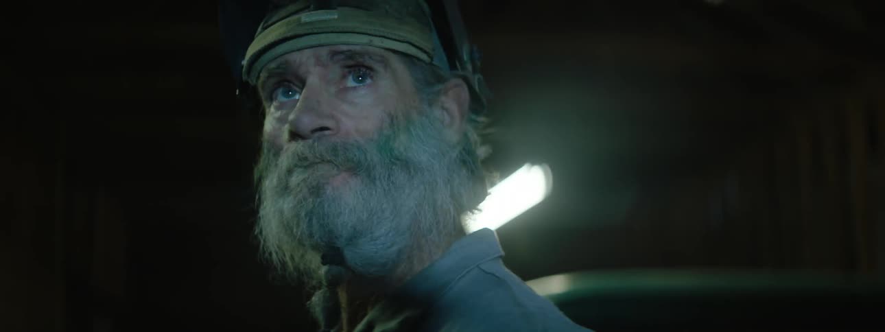 Lights flicker around a man who has the visor of his welding helmet up