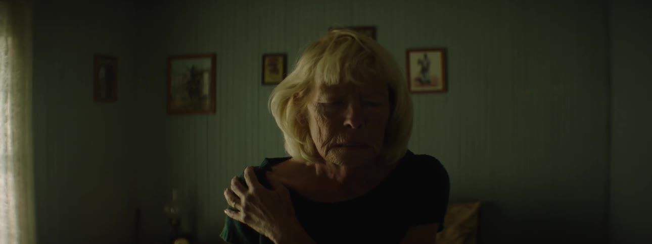 A woman removes her dark glasses and adjusts her sweater