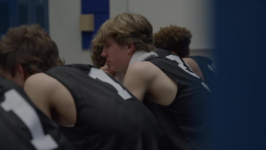 A group of teen athletes sitting together in a locker room after a game