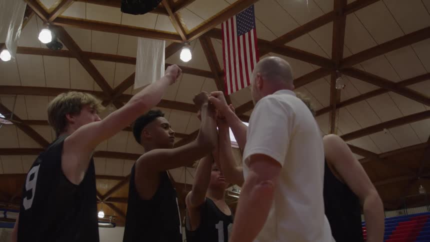 Coach and players join hands in a motivational gesture before the game