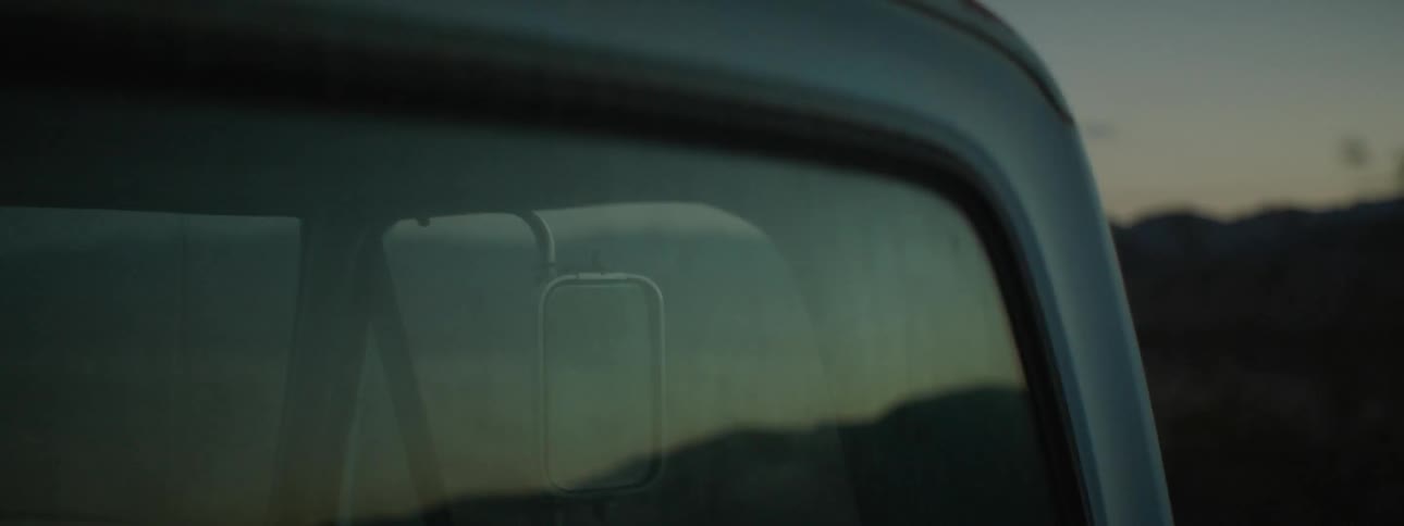 A pickup truck is driving in a hilly area during dusk