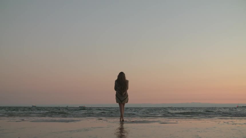 Woman standing on the shore close to the water