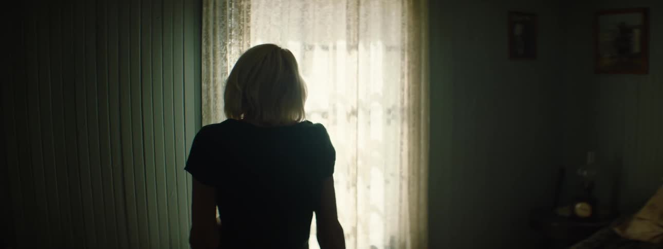 A woman holds an item in her hands in a dark room