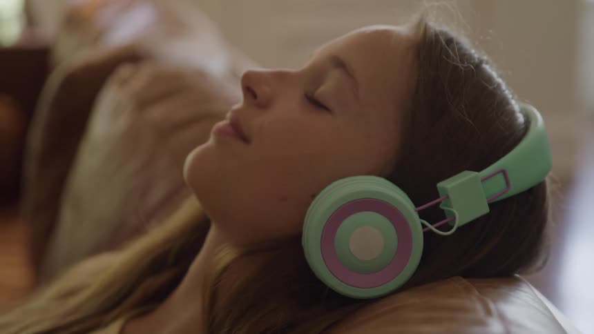 Woman relaxes on the couch while listening to music on headphones