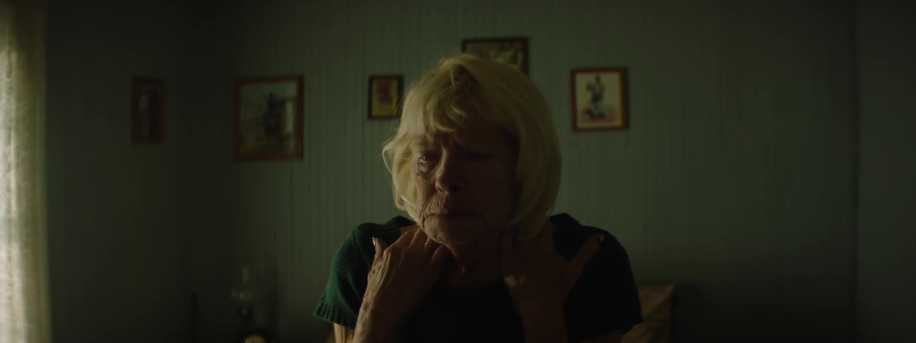 An elderly woman sits then shakes head no