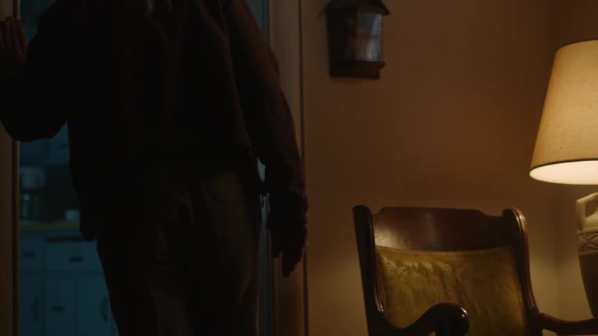 A woman sits in a chair by a lamp