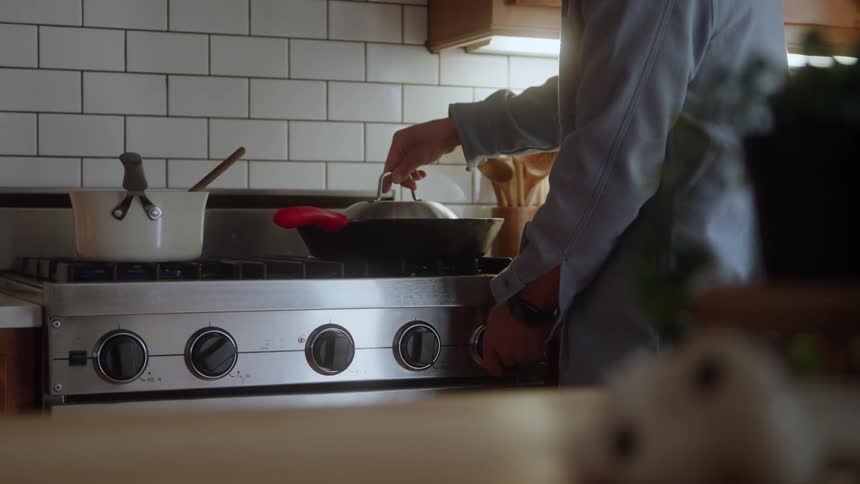 A person stirs a pot on the stove in a modern kitchen