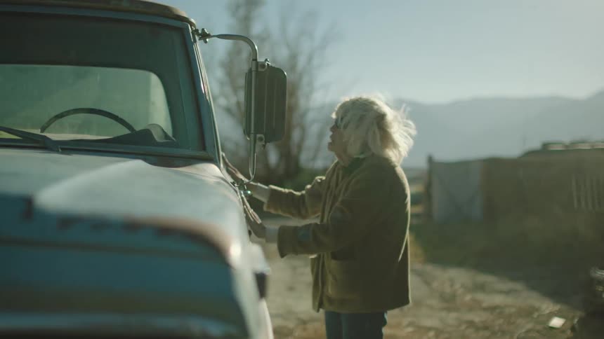 Elderly lady opens the door of a pickup truck