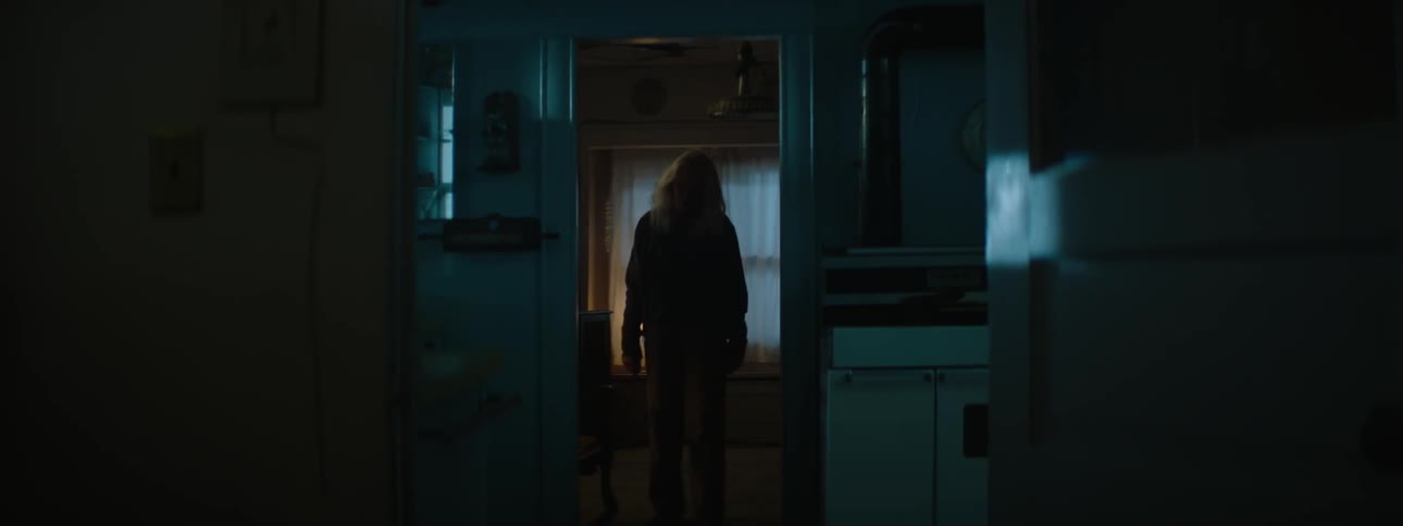 An older woman walks through a dim house