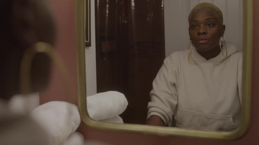 A woman leans over a sink looking down thoughtfully in a bathroom