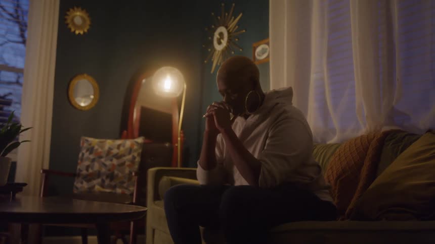Upset woman sitting alone on a sofa in a dimly lit living room