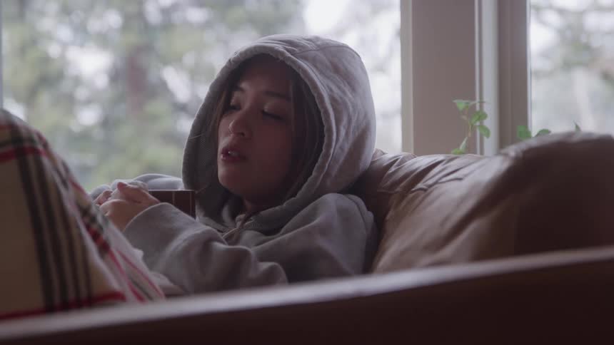 A sick women having coffee on couch in a living room