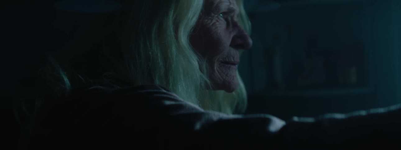 An older woman looks out of a window