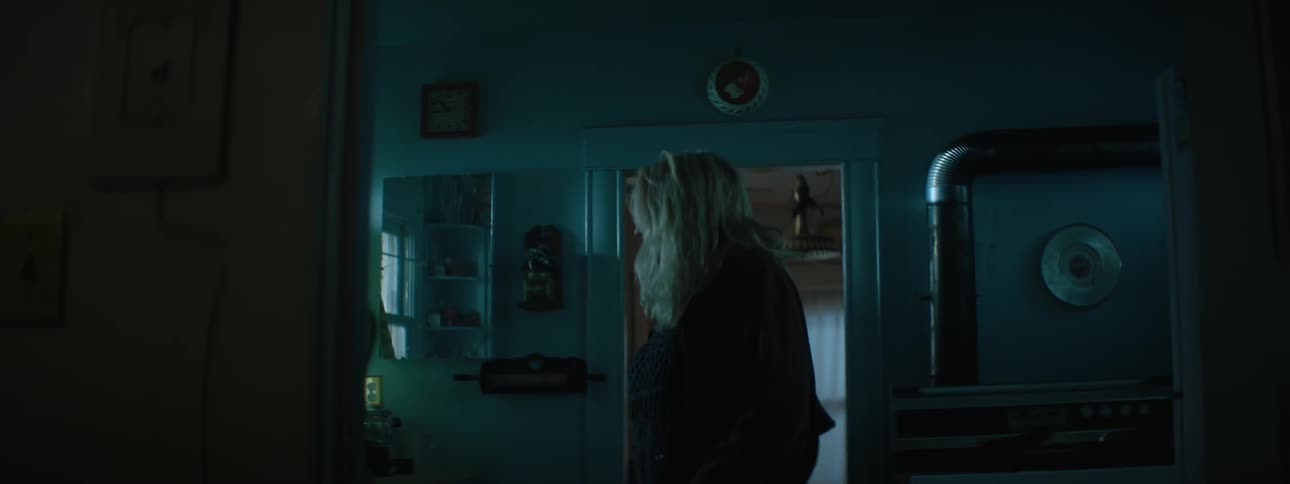 An elder woman looking around in her kitchen and looking out the windows