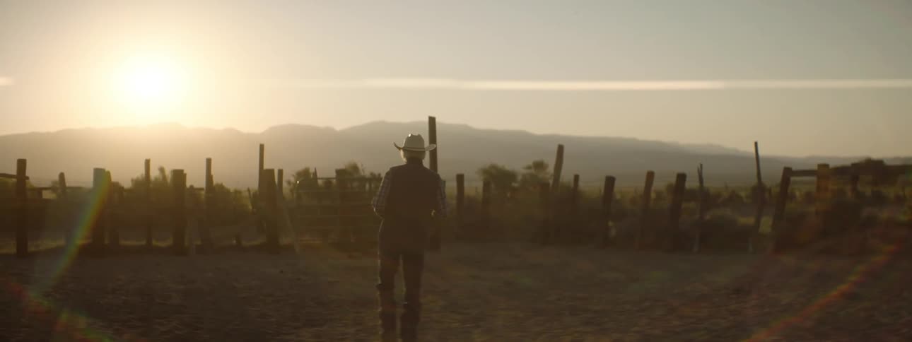 Older man walking and looking around outside on ranch while sun sets