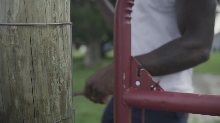 Farmer opening a gate and walking out on a family farm outdoors
