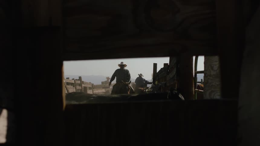 Men riding horses puts them into a barn