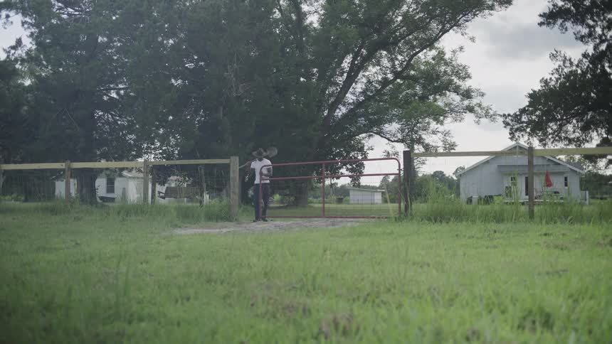 A farmer carrying a shovel walking on a family farm outdoors