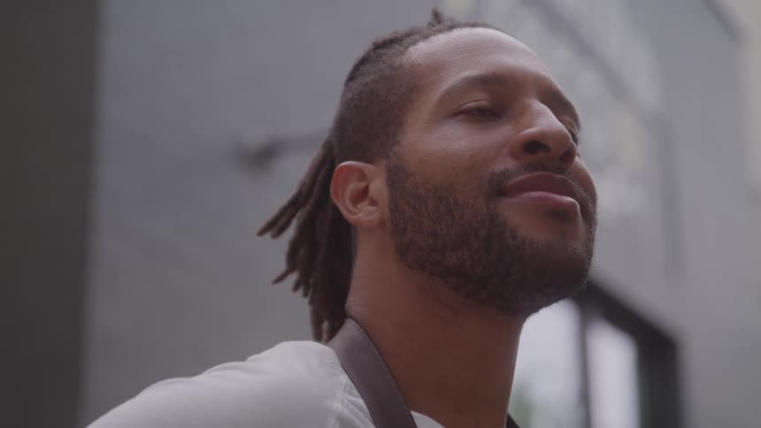 Closeup of a man calmly smiling and looking up against a blurred city background