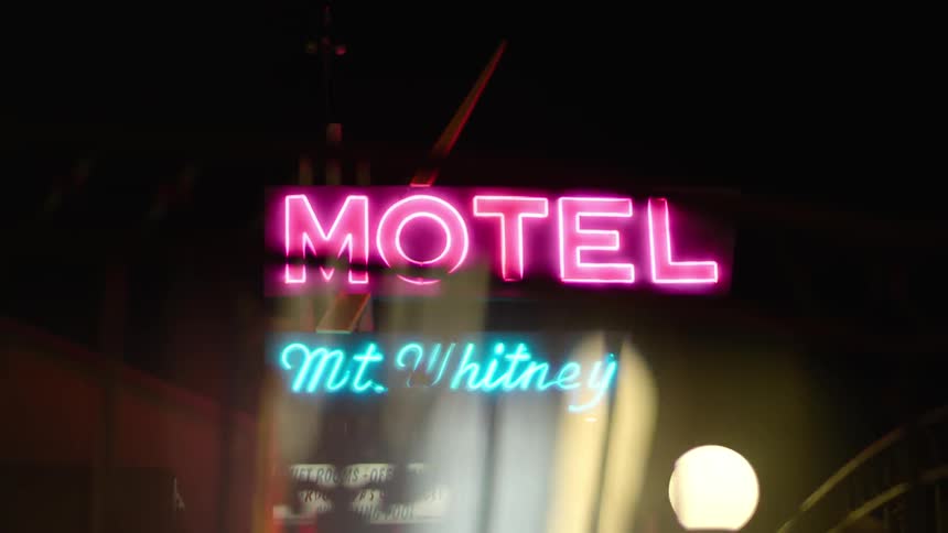 A motel sign shines in the dark night