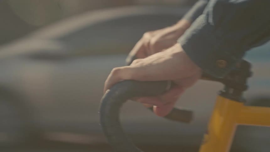 Man wearing a denim jacket riding on a yellow bike on the streets of a metropolitan area outdoors during day time