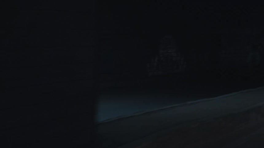 The video shows a slow pan across a dark concrete tunnel or underpass with a slightly raised curb the lighting is dim suggesting it is an enclosed space and there are dark plain walls visible on both sides