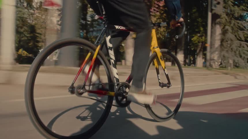 A man is riding a bicycle down a street with cars in the background
