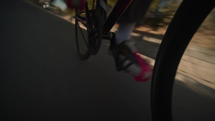 Foot on a pink bicycle pedal in motion on the asphalt