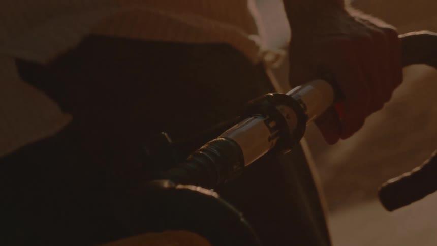 Hand grips the bicycle handlebar under the golden sunset light
