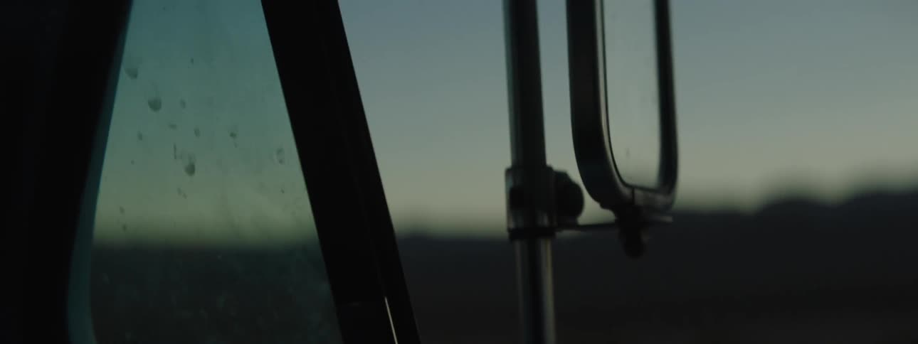 The side mirror of a truck traveling at dusk
