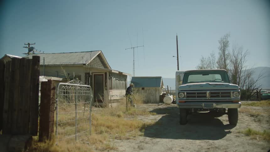 A person slowly exits a house walking towards a vehicle