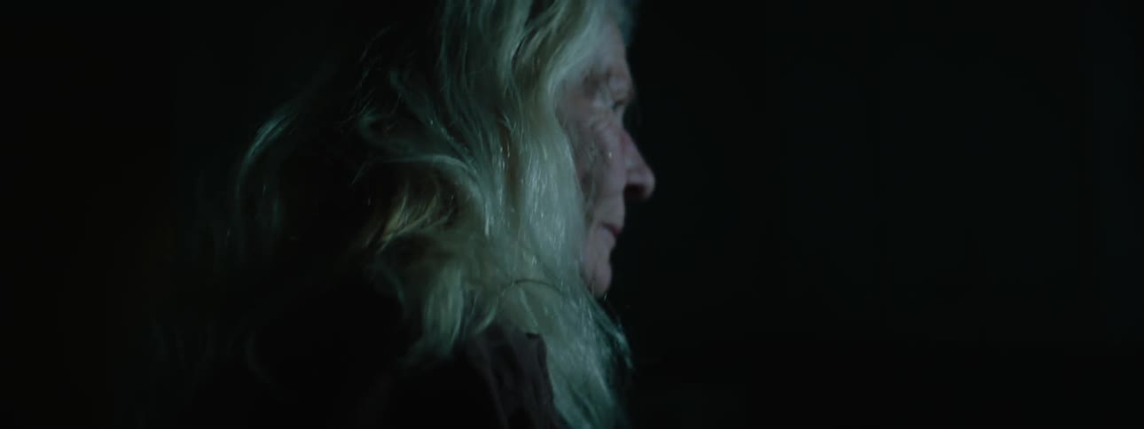 An elder woman looking around in a dark space