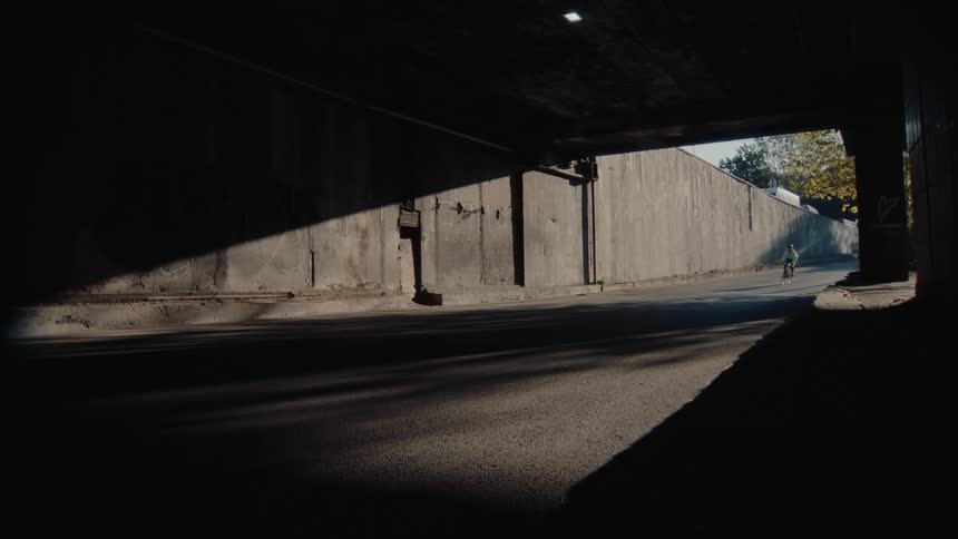 Cyclist rides through a tunnel partially lit by the evening light