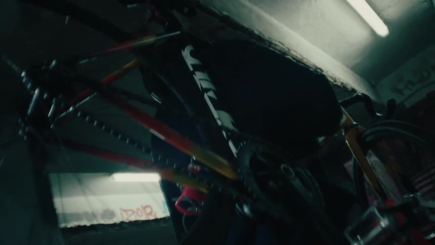 Person carries a bicycle up a staircase in a dimly lit indoor space