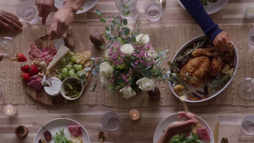 A group of people gather around a dining table at midday enjoying a variety of meals as sunlight streams in highlighting the vibrant spread and lively atmosphere