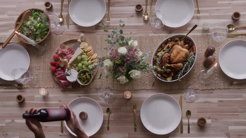 Food and drinks presented on a white table with a small group of people around interacting with elements on the table indoors