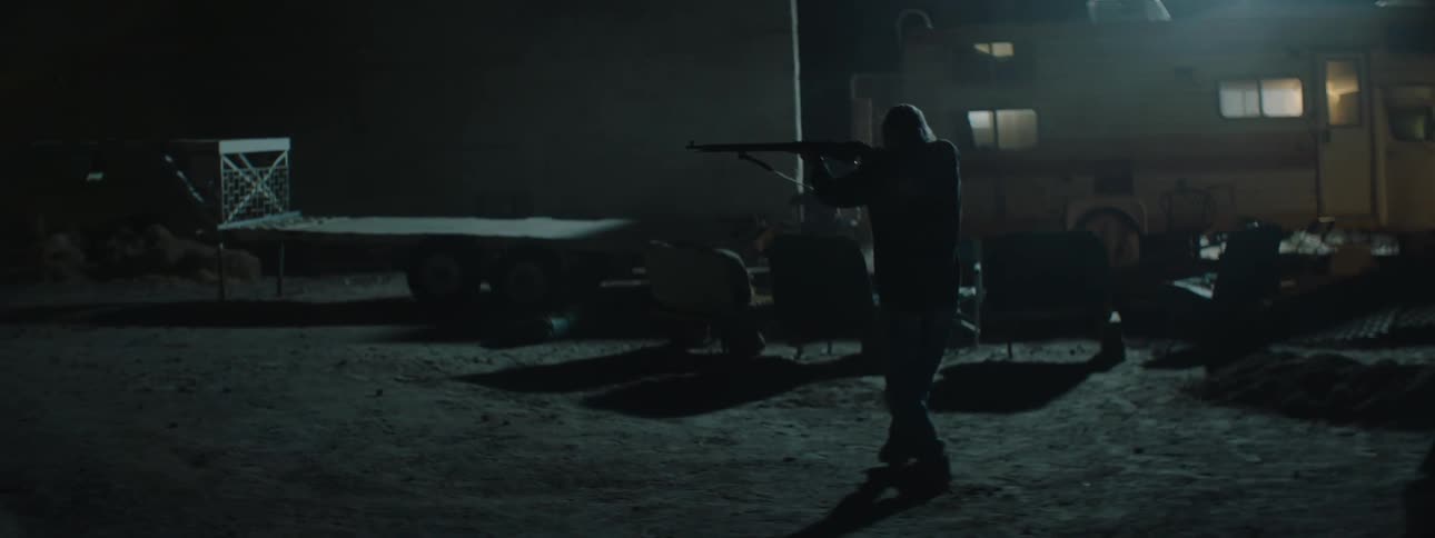 A person walks in his front yard with a rifle