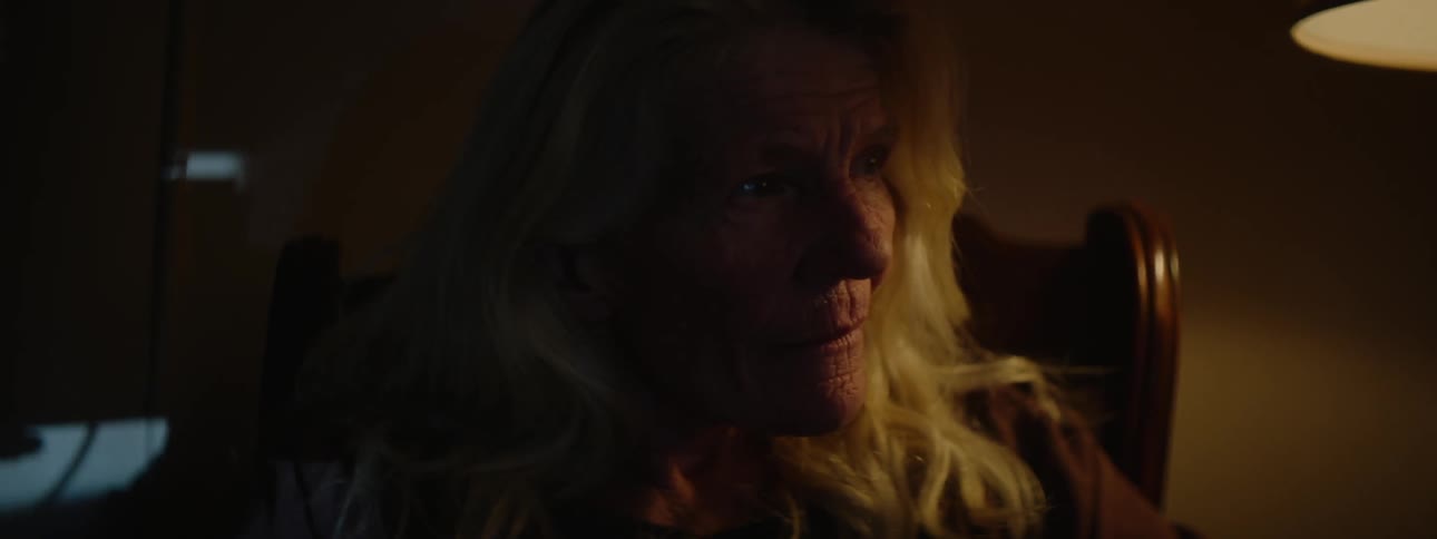 A woman sits in a dark living room