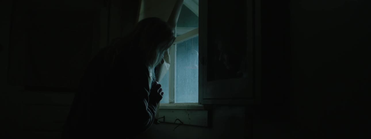 A woman looks out a window at bright flashing lights
