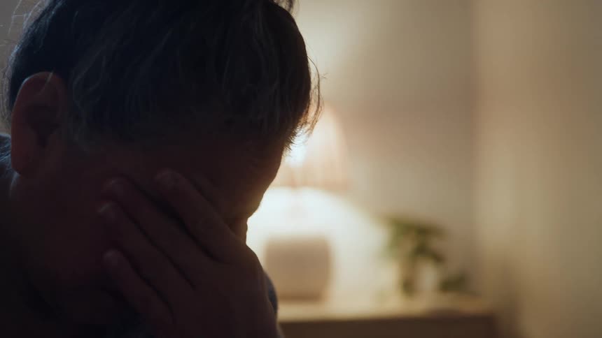 An elderly woman covering her face with her hand conveying a sense of sadness or despair