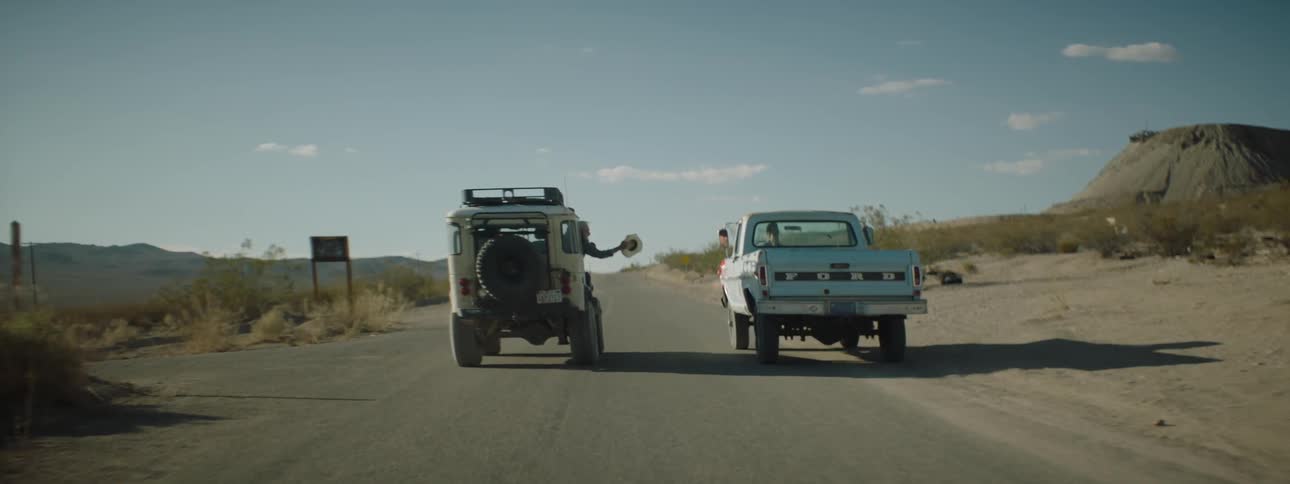 One person rides along a truck waving it down