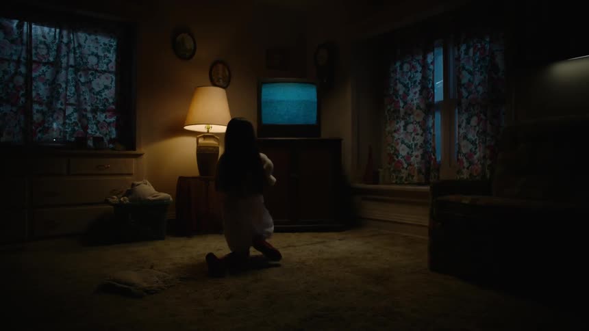 A child sitting on a floor looking at a staticky television