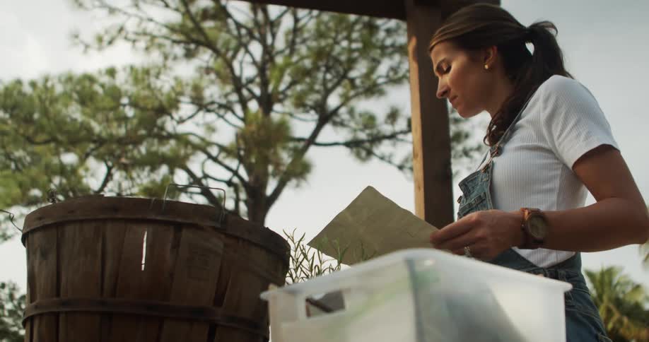Young woman standing outdoors in a shelter reading from a piece of paper during day time