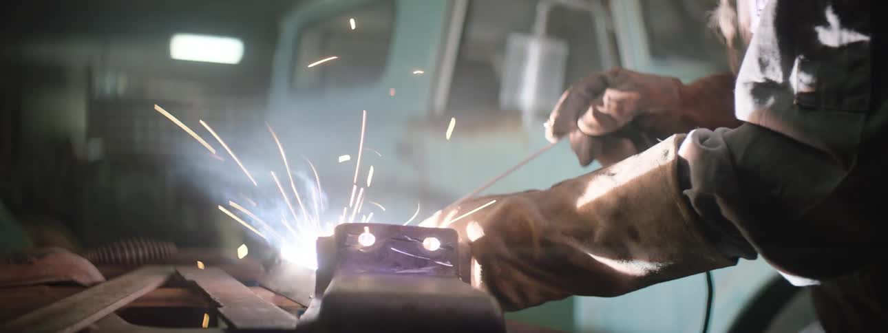 Man wearing welding helmet is welding in a garage