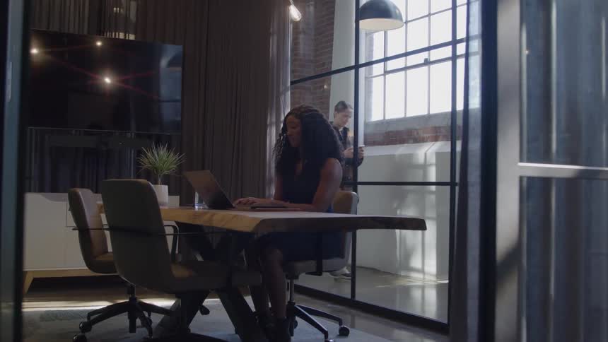 Woman works alone in a meeting room lit by natural light